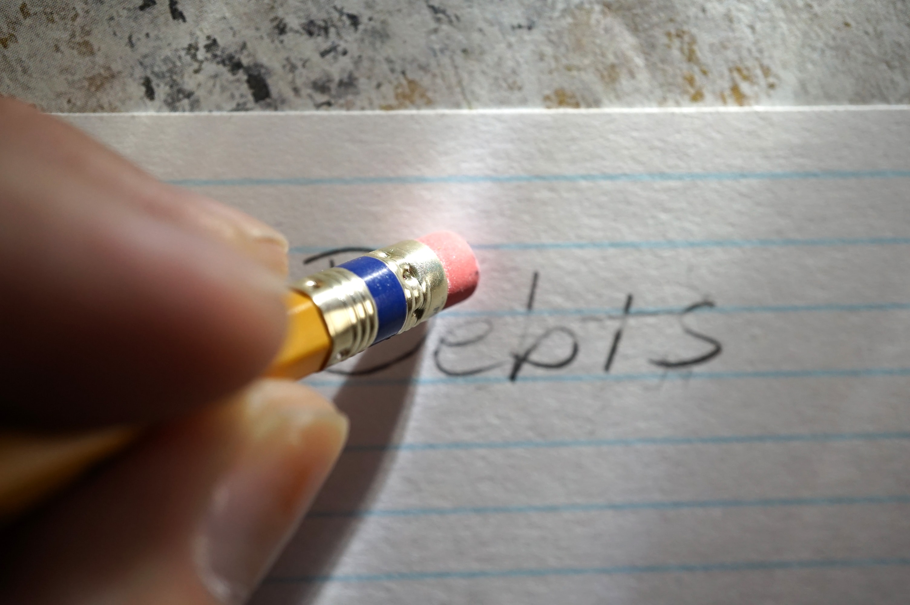 pencil erasing the word "debt" on a piece of paper