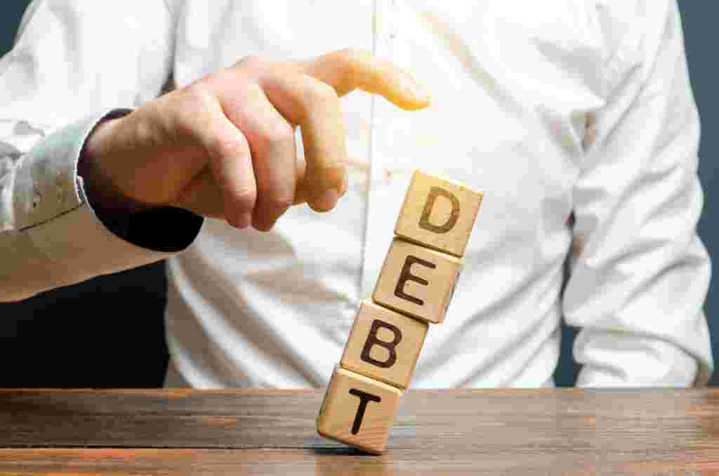A businessman pushes down a tower of cubes with the word Debt. concept of financial relief, loan restructuring. Financial stability and independence.