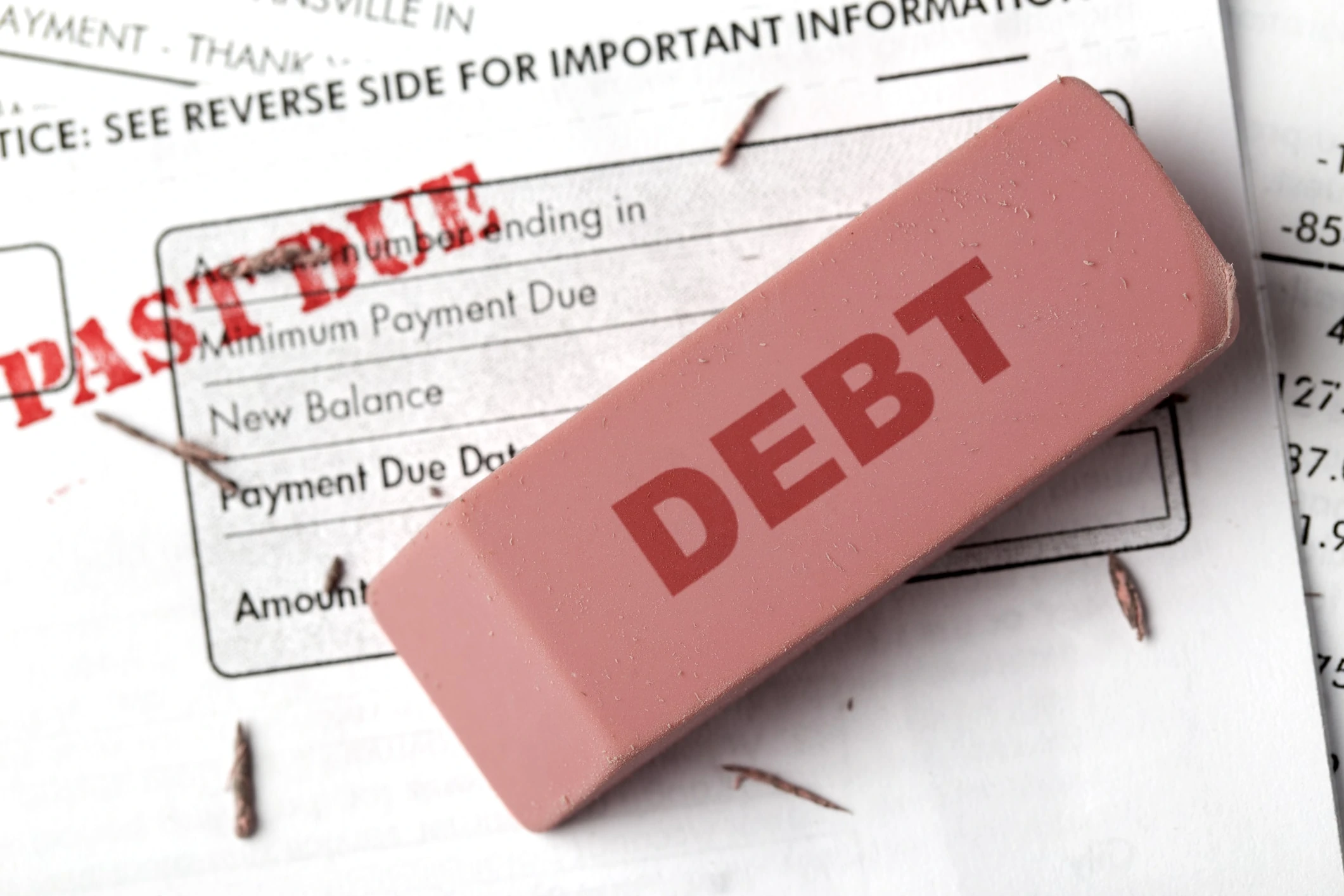 Debt relief concept. An eraser with the word "DEBT" on it erasing past due bills.