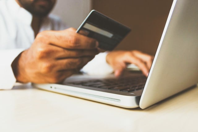 man in debt on his laptop while holding his credit card