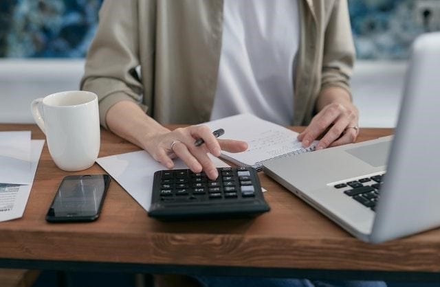 woman calculating her tax debt using a calculator