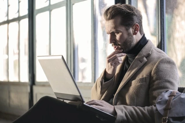 man thinking about payment deferral programs on his laptop