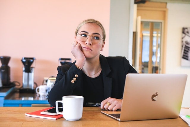 woman thinking about refinancing a mortgage to pay off debt on her laptop